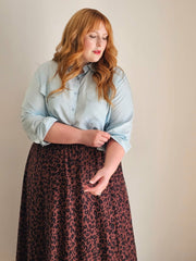 Woman wearing a light blue shirt and leopard print skirt against a plain background