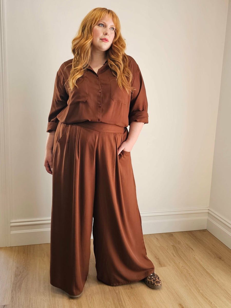 Woman wearing a pair of chocolate coloured wide leg pants and shirt by Hope and Harvest.